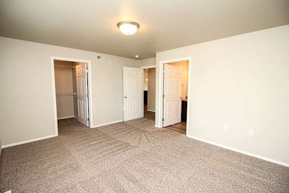 A room with carpeted floor and two open doors.