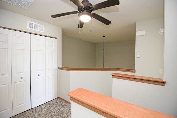 A room with a ceiling fan and a long wooden bench.