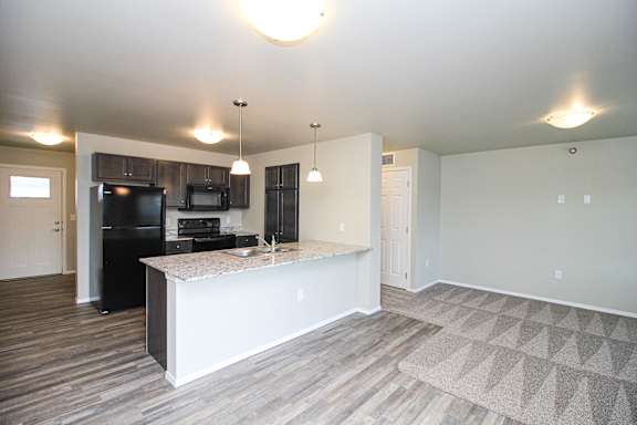 A kitchen with a black refrigerator, microwave, and oven.