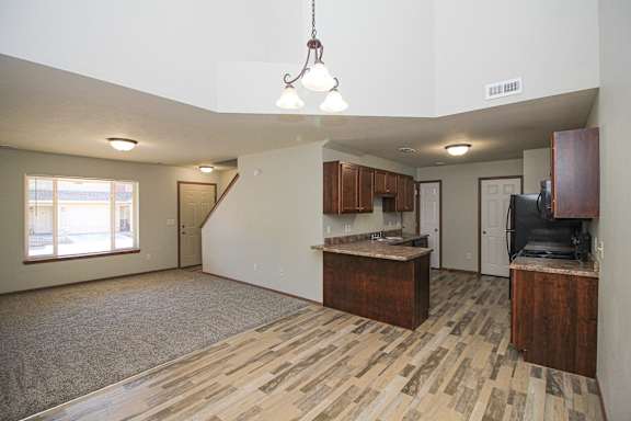 A kitchen area with wooden flooring and a staircase in the background.