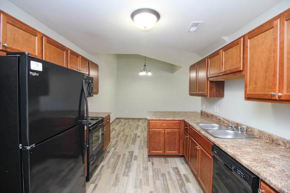 A kitchen with black appliances and wooden cabinets.