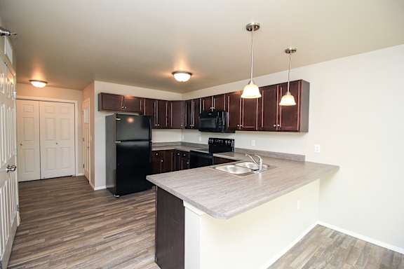 A kitchen with a refrigerator, sink, and cabinets.