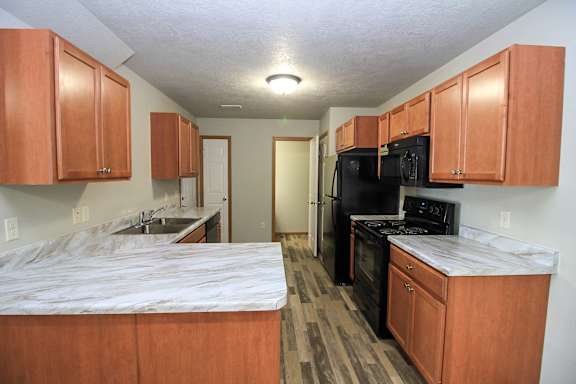 A kitchen with wooden cabinets and a marble countertop.
