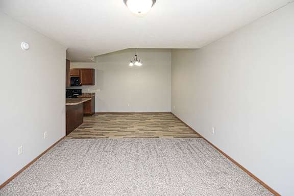 A large empty room with a carpeted floor and a ceiling light.