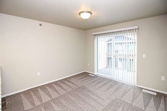 A room with a carpeted floor and a window with blinds.