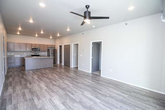 A spacious room with a ceiling fan and lighting fixtures.