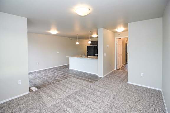 A spacious living room with a carpeted floor and a bar area.