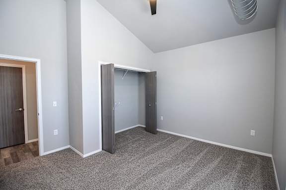 A room with a carpeted floor and a ceiling fan.