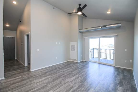 A room with a ceiling fan and sliding glass doors.