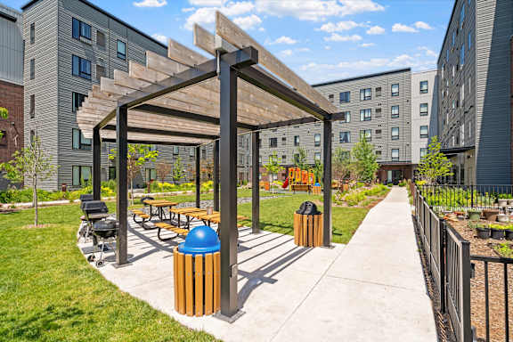 a park with benches and a pergola on a sidewalk