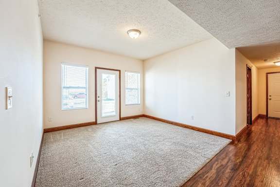 the living room and dining room of an empty house with wood floor and white walls