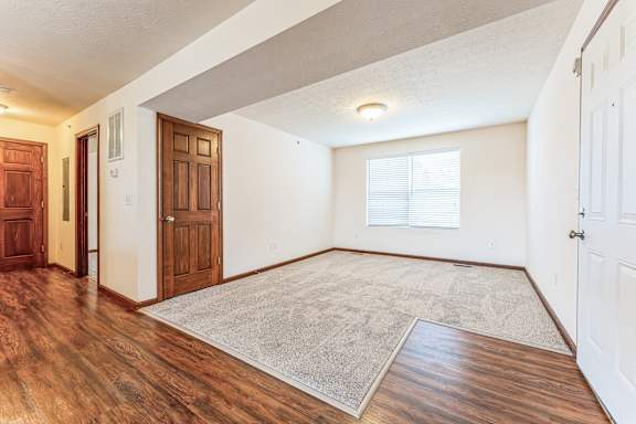 the living room and entryway of a house with wood flooring and white walls