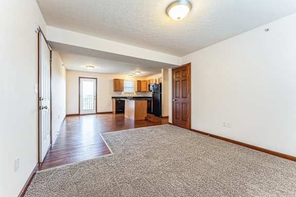 an empty living room and kitchen with wood floors and white walls