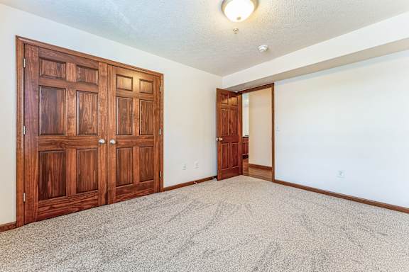 an empty living room with wood doors and carpet