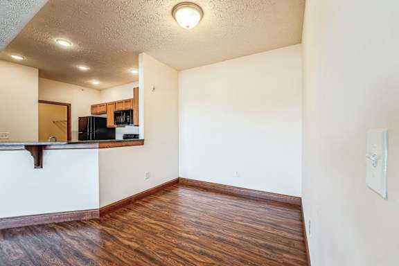the living room and kitchen of an empty apartment with wood flooring