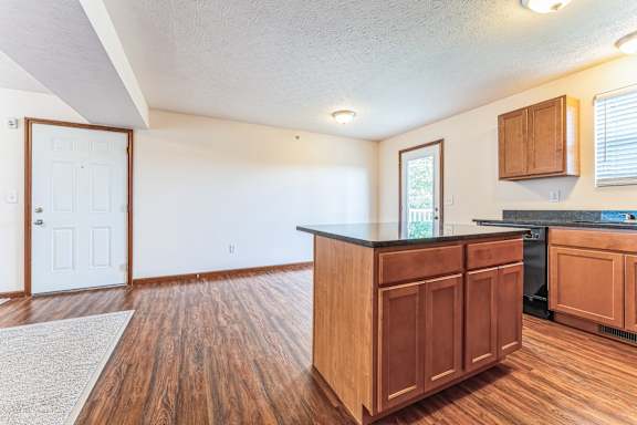 the kitchen and living room of an empty house with wood flooring and a counter