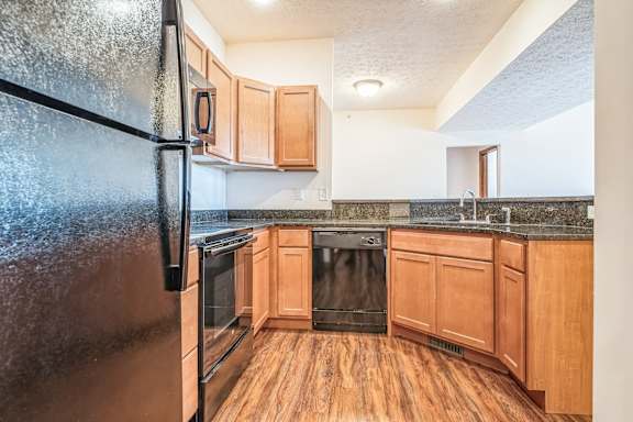 a kitchen with wooden cabinets and a stainless steel refrigerator