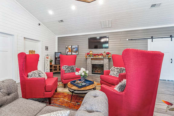 a living room with red chairs and a fireplace