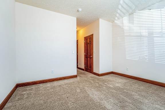 an empty living room with white walls and a wooden door