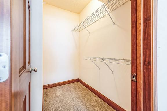 a walk in closet with a wood door and a white wall with a hanging rack