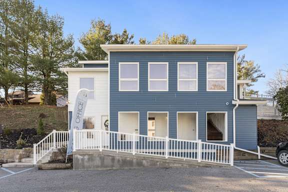 the front of a blue house with a porch and a white fence