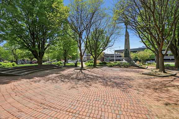A monument stands in the middle of a brick courtyard.