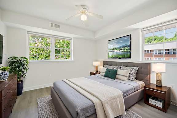 A bedroom with a bed, a ceiling fan, and a large window.