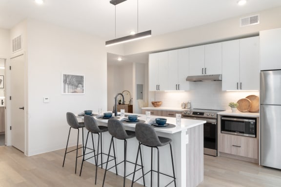a kitchen with white cabinets and a counter with three stools at ORRIS Apartments, Rocky River, Ohio