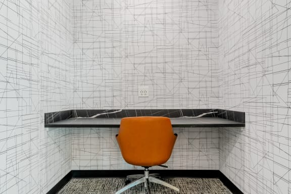 an orange chair in an office with white walls and a black shelf at TREO Apartments, Cleveland, 44116