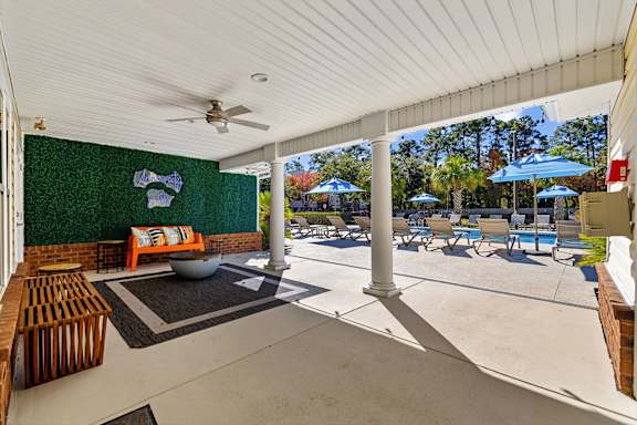 A patio with a table and chairs and a ceiling fan.