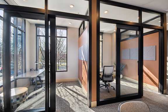 A room with a table and chairs with a glass wall separating it from another room.