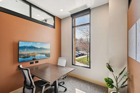 A room with a brown wall and a painting of a lake and mountains on it.