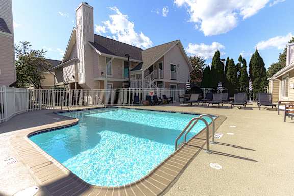 A small pool in a backyard with a white fence. at AVIA Lofts on Victors Way, Ann Arbor