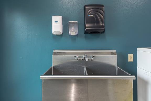 A sink with a soap dispenser and hand dryer on a wall. at AVIA Lofts on Victors Way, Ann Arbor, 48108