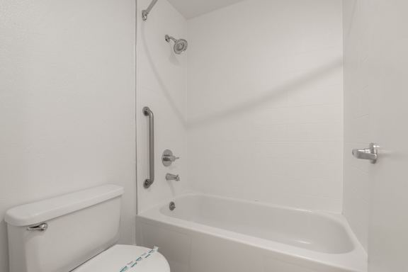 A white toilet sits next to a white bathtub in a bathroom. at AVIA Lofts on Parkway, Vancouver