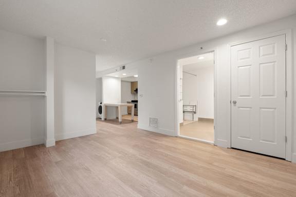 A room with white walls and wooden flooring with a table and chairs in the background. at AVIA Lofts on Parkway, Vancouver Washington
