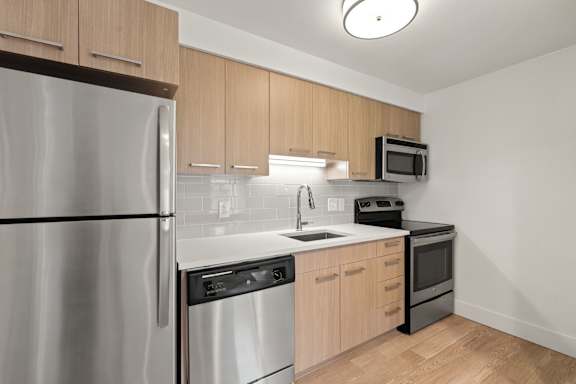 Kitchen with granite counter, sink and fridge at AVIA Lofts on Parkway, Washington , 98662