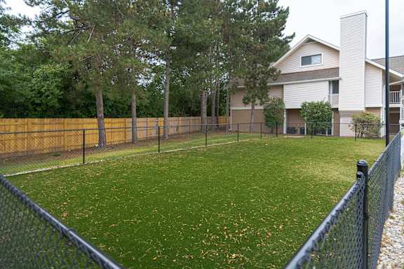 A backyard with a fence and a house in the background. at AVIA Lofts on Victors Way, Ann Arbor Michigan