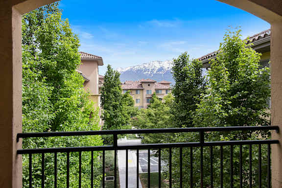 A view from a balcony looking out at a street with houses and trees.