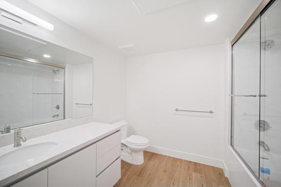 A white bathroom with a glass shower stall and a toilet in the corner.