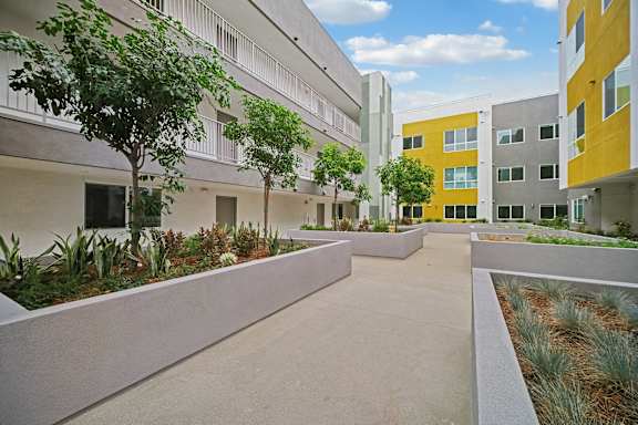 A courtyard with a concrete floor and a yellow building in the background.