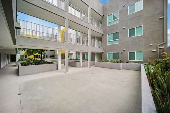 A large open courtyard with a concrete floor and a building with balconies on the upper floor.