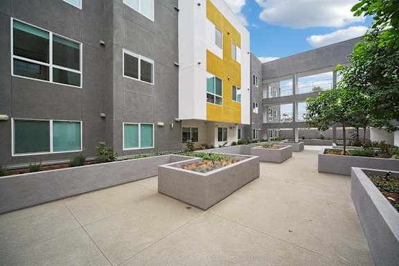 A courtyard with a planter box in the middle surrounded by buildings.