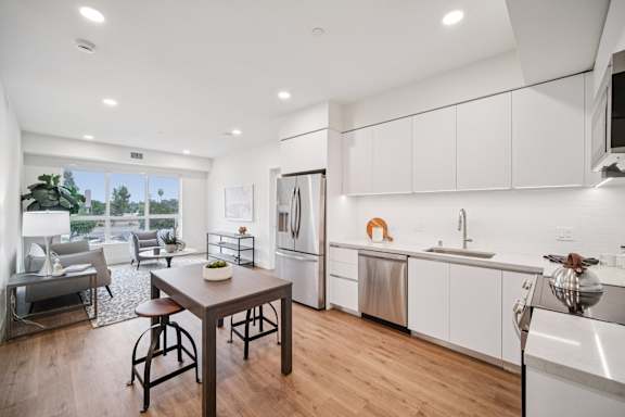 A modern kitchen with white cabinets and a wooden table.
