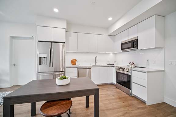 A modern kitchen with a wooden table and a plant on it.