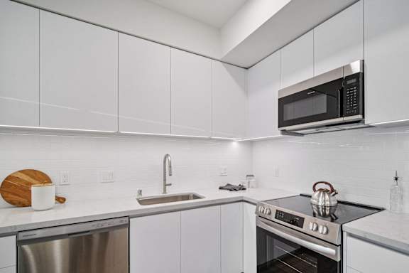 A modern kitchen with a stainless steel dishwasher, a microwave, and a stove top oven.
