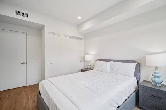A bedroom with a bed, nightstand, and two lamps.