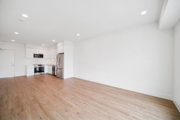 A spacious room with wooden flooring and white walls.