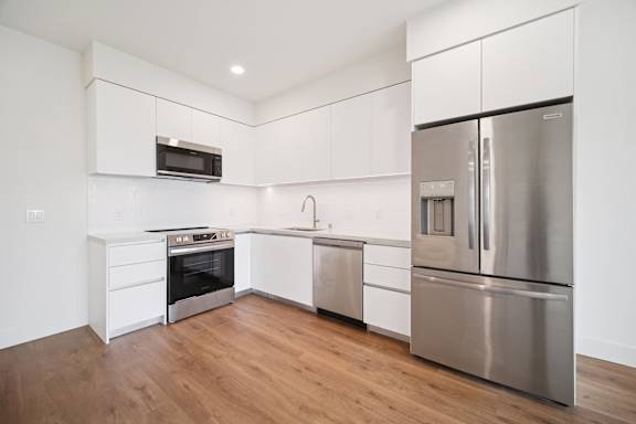 A modern kitchen with stainless steel appliances and white cabinetry.