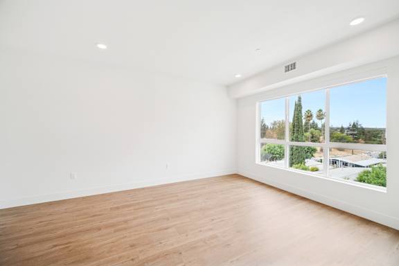 Empty room with a view of trees and buildings outside.